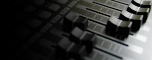Close-up of an audio mixing console with sliding faders and labeled buttons, partially in shadow, reflecting the intricate precision needed for seamless video distribution.